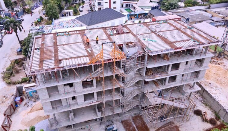 Aerial view of a multi-storey reinforced concrete frame under construction with a tower crane on site